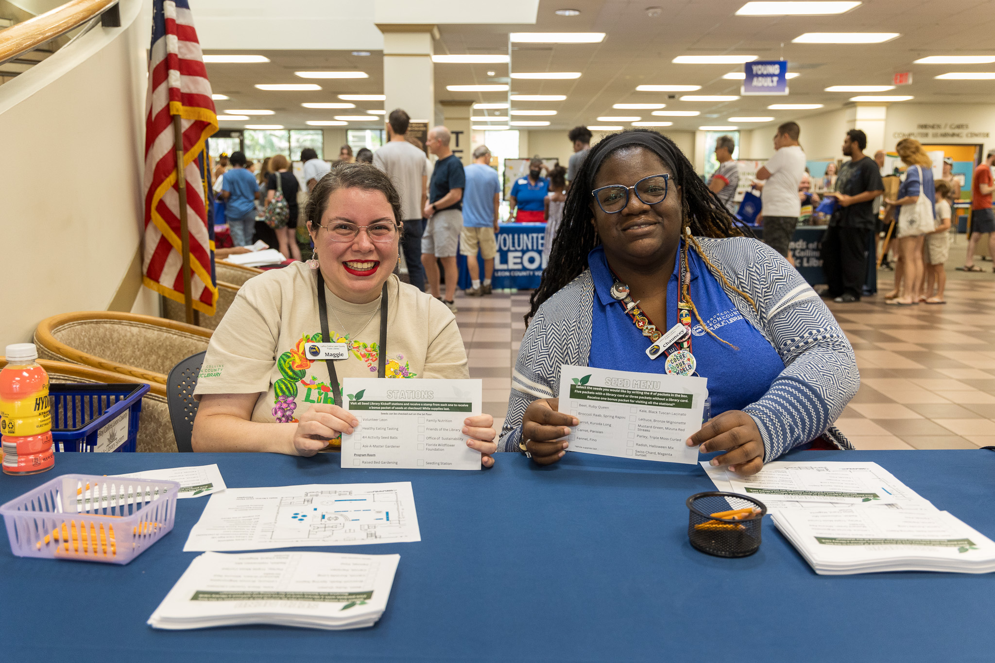 Two library staff members showing off Seed Library kickoff passports at the Main Library.